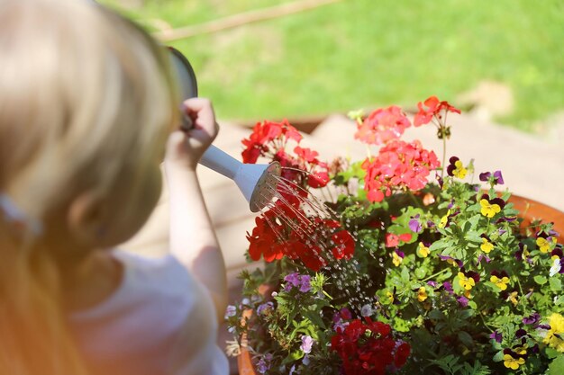 Foto kleines mädchen gießt blumen im hinterhof