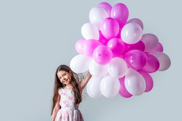 Kleines Mädchen hält Heliumballons. Kinder glückliches kleines Mädchen mit bunten Luftballons. Porträt eines glücklichen Teenagers oder Jugendlichen. Kindergeburtstag feiern Feiertag. Kleines Mädchen mit Luftballons