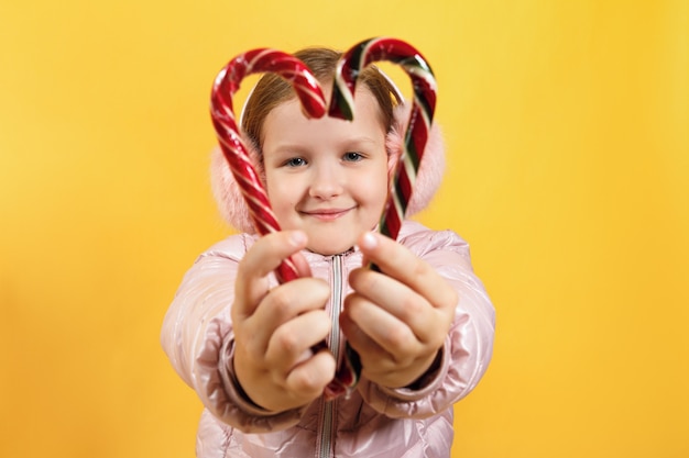 Kleines Mädchen hält Weihnachtssüßigkeit in Form eines Herzens.