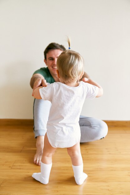 Kleines Mädchen Händchen haltend von Papa auf dem Boden sitzend