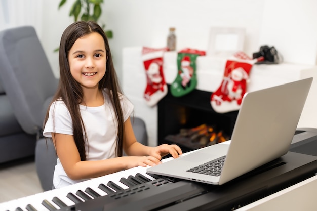 Kleines Mädchen hat Online-Unterricht mit Lehrer zum Klavierspielen zur Weihnachtszeit