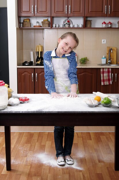 Foto kleines mädchen hilft in einer unordentlichen küche zu backen