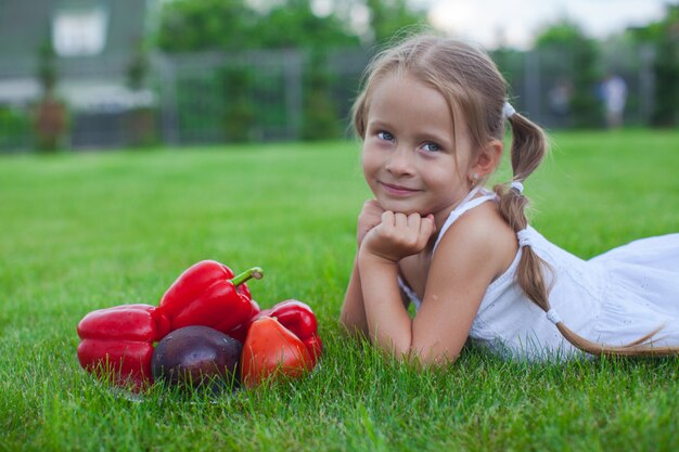 Kleines Mädchen im Garten mit einem Teller mit Gemüse