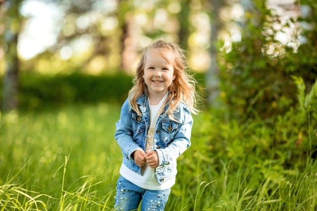 kleines Mädchen im Jeansanzug geht im Frühjahr in den lila Garten