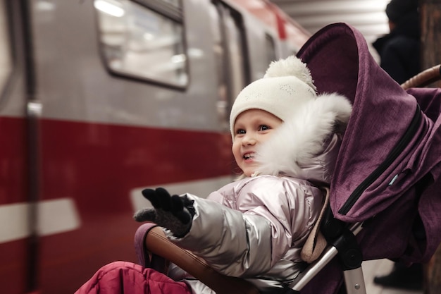 Kleines Mädchen im Kinderwagen auf der U-Bahn-Station im öffentlichen Nahverkehr