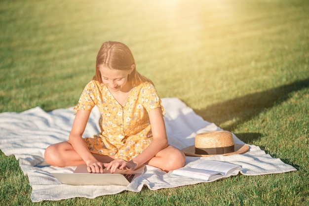 Kleines Mädchen im Park mit einem Laptop