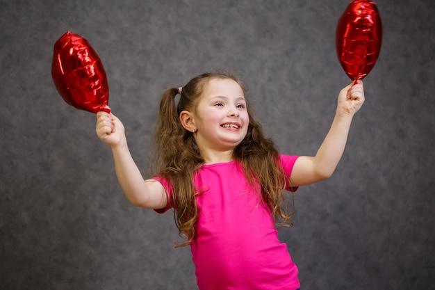 Kleines Mädchen im rosa T-Shirt spielt mit Luftballons