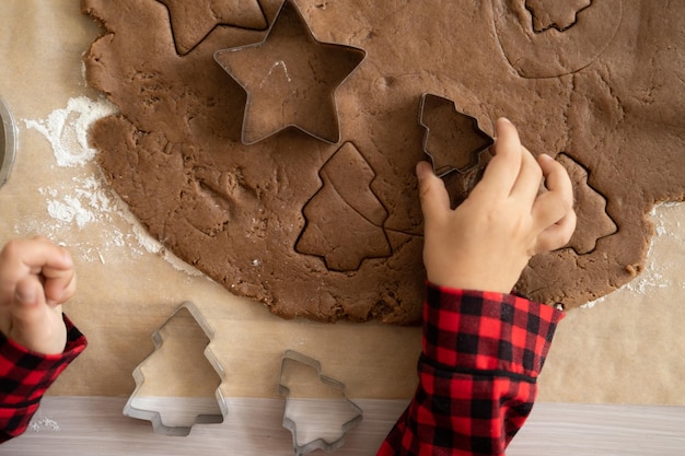 kleines Mädchen im roten Pyjama, das festlichen Lebkuchen in der weihnachtlich dekorierten Küche kocht