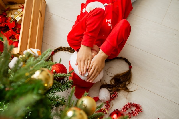 kleines Mädchen im roten Pyjama feiert das neue Jahr und Weihnachten auf dem Boden liegend