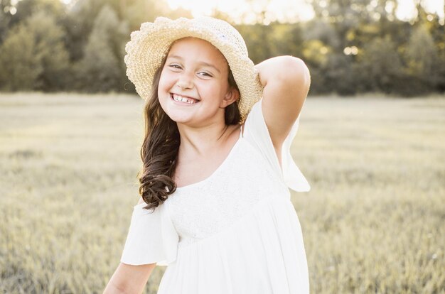 Kleines Mädchen im Sommer, das Spaß an der Natur hat, sorglos lächeln und im Sonnenlicht lachen