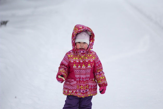 Kleines Mädchen im verschneiten Park im Winter