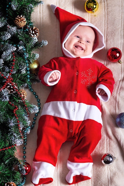 Kleines Mädchen im Weihnachtsmann-Kostüm, das auf einer Decke liegt