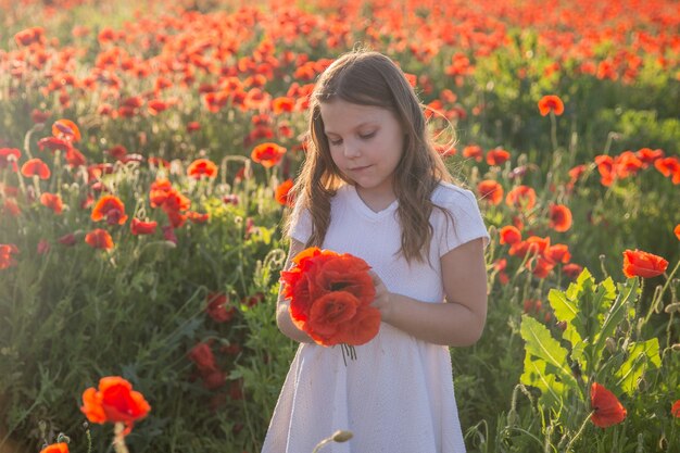 Kleines Mädchen im weißen Kleid auf Mohnfeld, Sommer