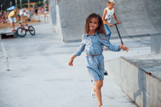 Kleines Mädchen in blauer Kleidung, das in der Stadt posiert, wenn es sich auf die Rampe lehnt