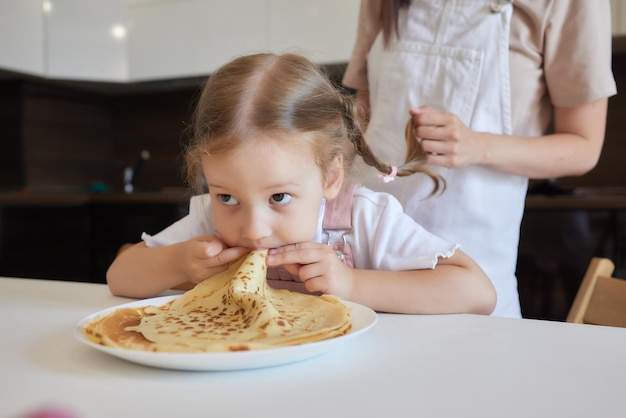 Kleines Mädchen in der Küche isst Pfannkuchen