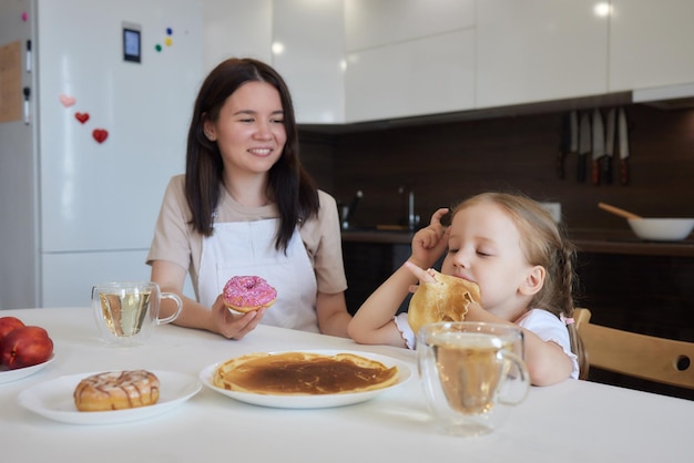 Kleines Mädchen in der Küche isst Pfannkuchen