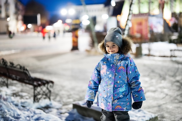 Kleines Mädchen in der Nachtstadt im Winter