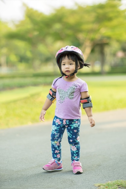 Kleines Mädchen in der Radfahrenabnutzung bereit, Reitbalancenfahrrad im Park zu lernen