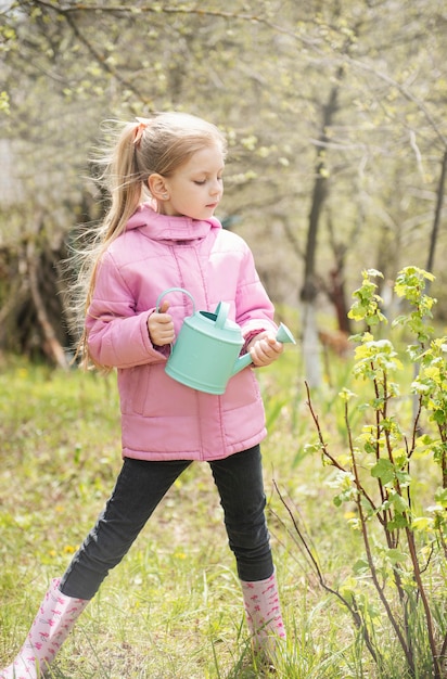 Kleines Mädchen in einem Garten mit grüner Gießkanne