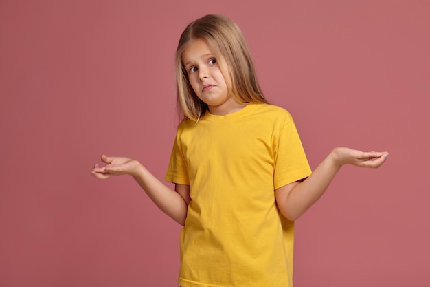 Kleines Mädchen in einem gelben T-Shirt. kennt die Antwort nicht