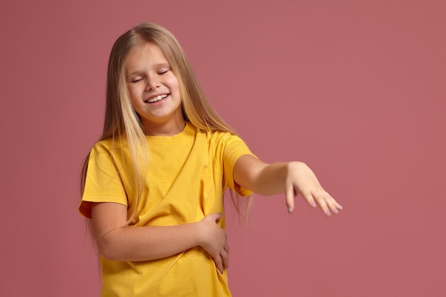 Kleines Mädchen in einem gelben T-Shirt. schüchtern zeigt