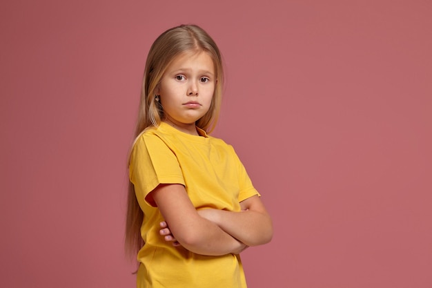 Kleines Mädchen in einem gelben T-Shirt. sieht beleidigt aus