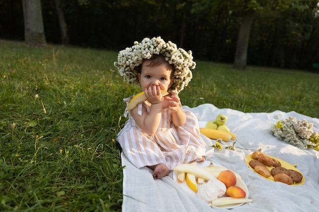 Kleines Mädchen in einem gestreiften Kleid auf einem Picknick in einem Stadtpark