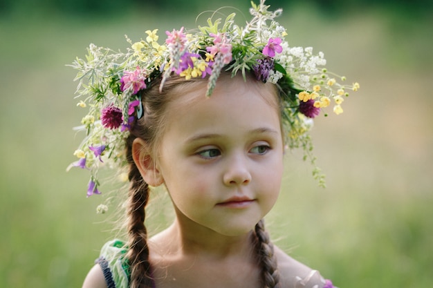 kleines Mädchen in einem Kranz aus wilden Blumen im Sommer