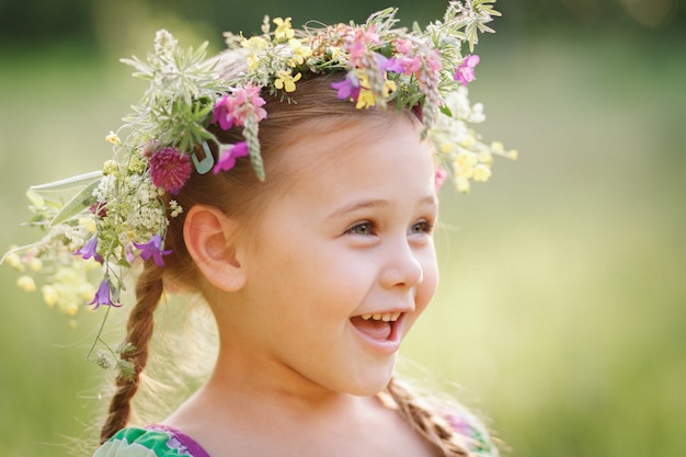kleines Mädchen in einem Kranz aus wilden Blumen im Sommer