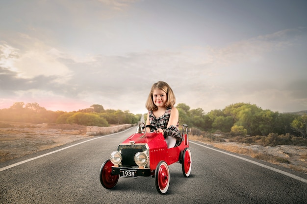 Kleines Mädchen in einem Spielzeugauto