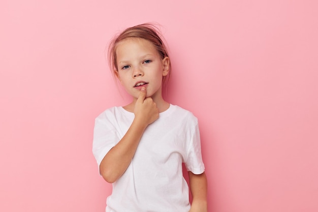 Kleines Mädchen in einem weißen T-Shirt lächelt rosa Hintergrund