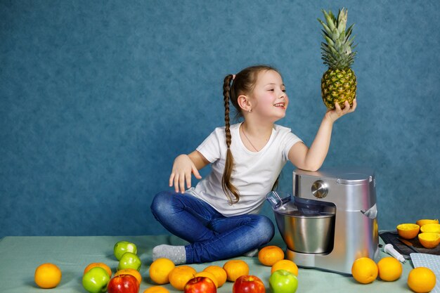 Kleines Mädchen in einem weißen T-Shirt liebt Früchte. Sie hält eine Ananas in ihren Händen