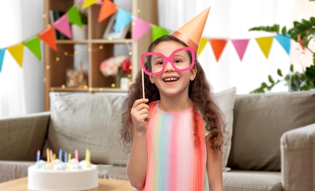 kleines Mädchen in Geburtstagsfeierhut mit Brille