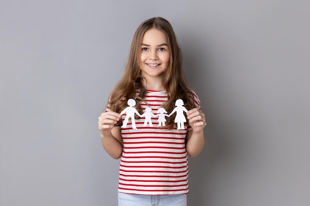 Kleines Mädchen in gestreiftem T-Shirt, das Papierfamilienkettenbeziehungen zwischen Kindern und Eltern hält