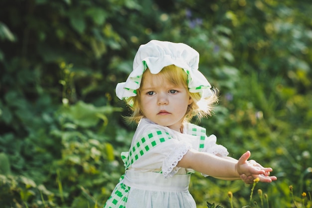 Kleines Mädchen in grün-weißem Kleid, das im Garten spaziert 4649