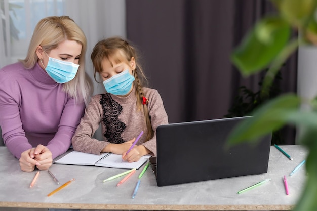 kleines Mädchen in medizinischer Maske, das zu Hause lernt. Epidemie Pandemie.