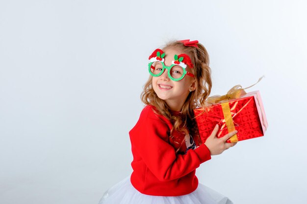 Kleines Mädchen in Nikolausmütze hält ein Geschenk auf weißem Hintergrund Weihnachtskonzept-Textraum