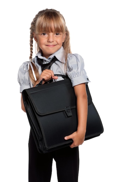 Kleines Mädchen in Schuluniform mit einer auf weißem Hintergrund isolierten Aktentasche
