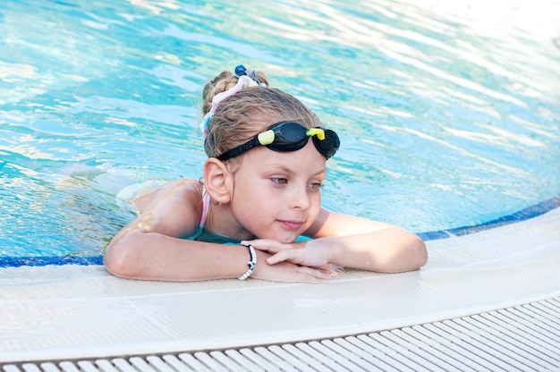 Kleines Mädchen in Schwimmbrille schwimmt im Pool