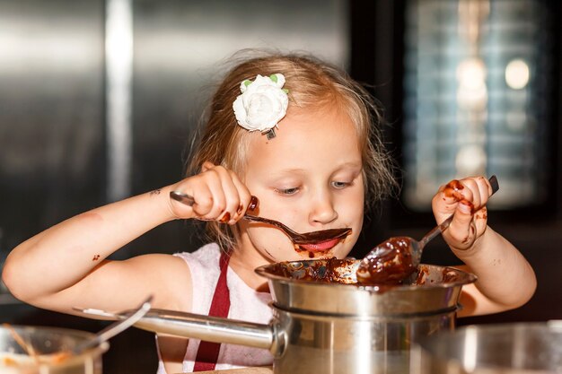 kleines Mädchen isst Schokolade mit einem Löffel