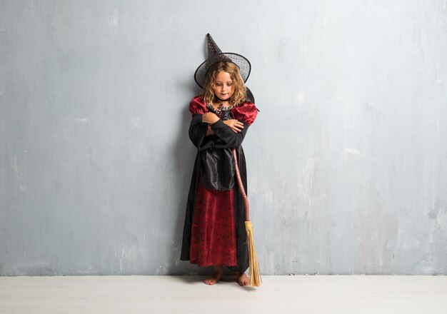 Kleines Mädchen kleidete als Hexe für Halloween-Feiertage mit ihren gekreuzten Armen an