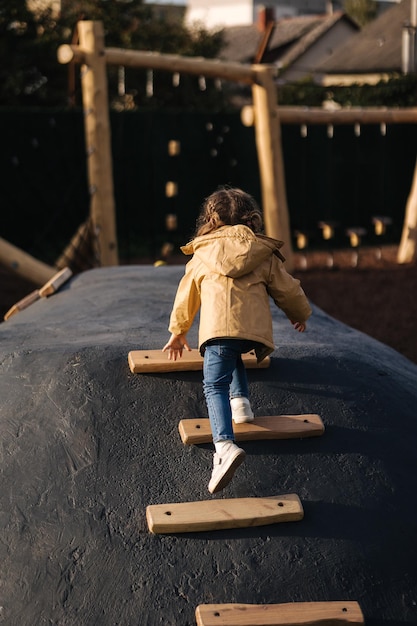 Kleines Mädchen klettert auf Spielplatz viel Energie den Hügel hinauf