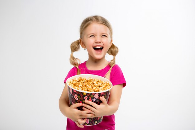 kleines Mädchen lächelt mit einem Eimer Popcorn