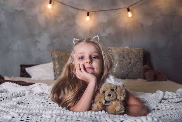 Kleines Mädchen lag mit Hundespielzeug im Bett