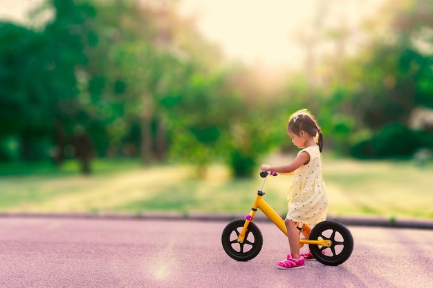 Kleines Mädchen lernt, Balancefahrrad im Park zu reiten