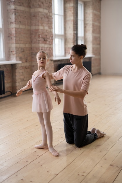 Kleines Mädchen lernt während ihres Ballettunterrichts mit Trainer in der richtigen Position zu stehen