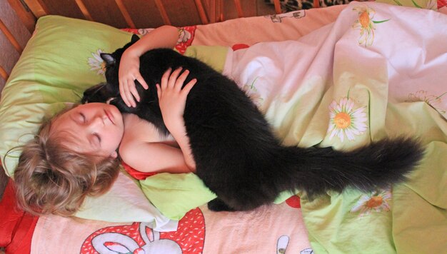 Kleines Mädchen liegt im Bett zusammen mit ihrer Katze zusammen mit Ihrem Haustier