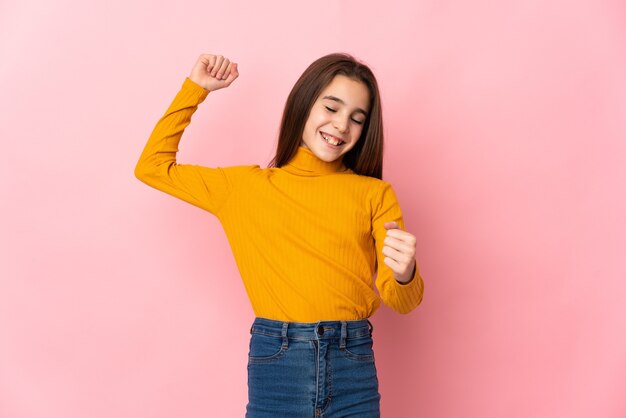 Kleines Mädchen lokalisiert auf rosa Wand, die einen Sieg feiert