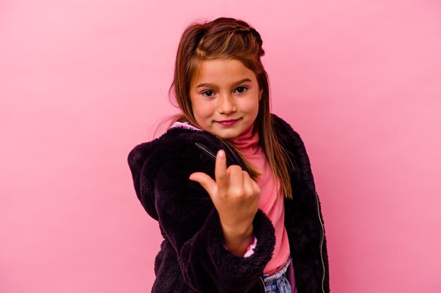 Kleines Mädchen lokalisiert auf rosa Wand, die mit dem Finger auf Sie zeigt, als ob die Einladung näher kommt