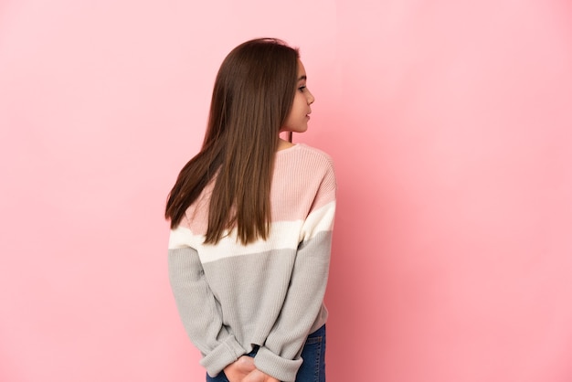 Kleines Mädchen lokalisiert auf rosa Wand in der hinteren Position und im Rückblick